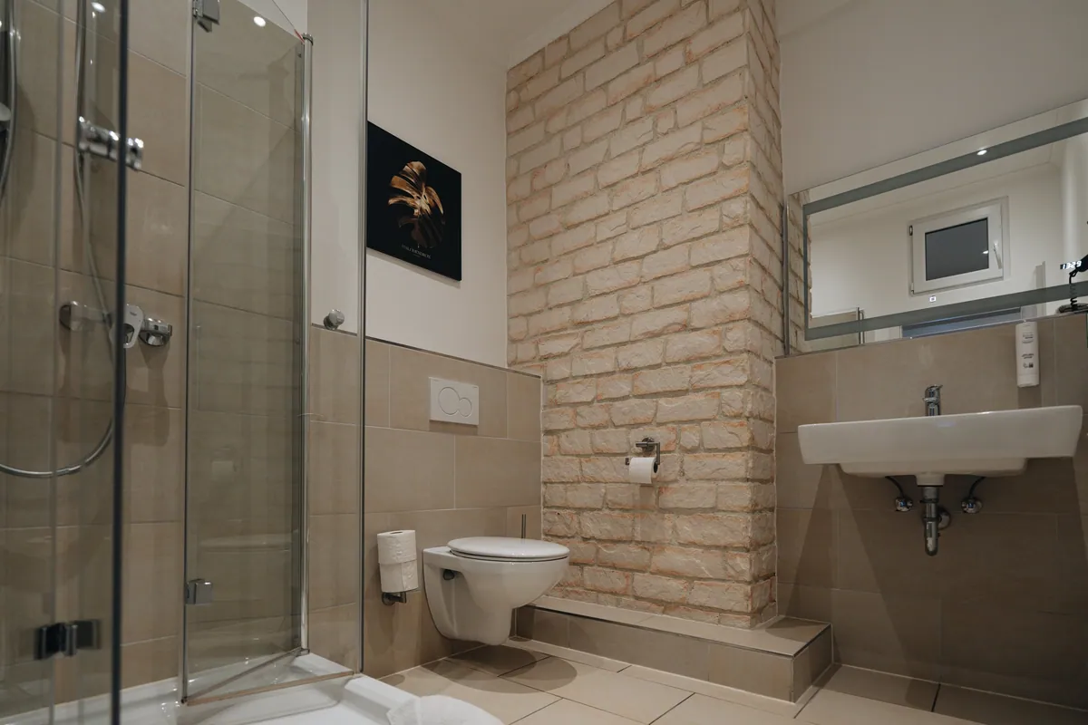 Badezimmer mit Ziegelwand und Glasdusche