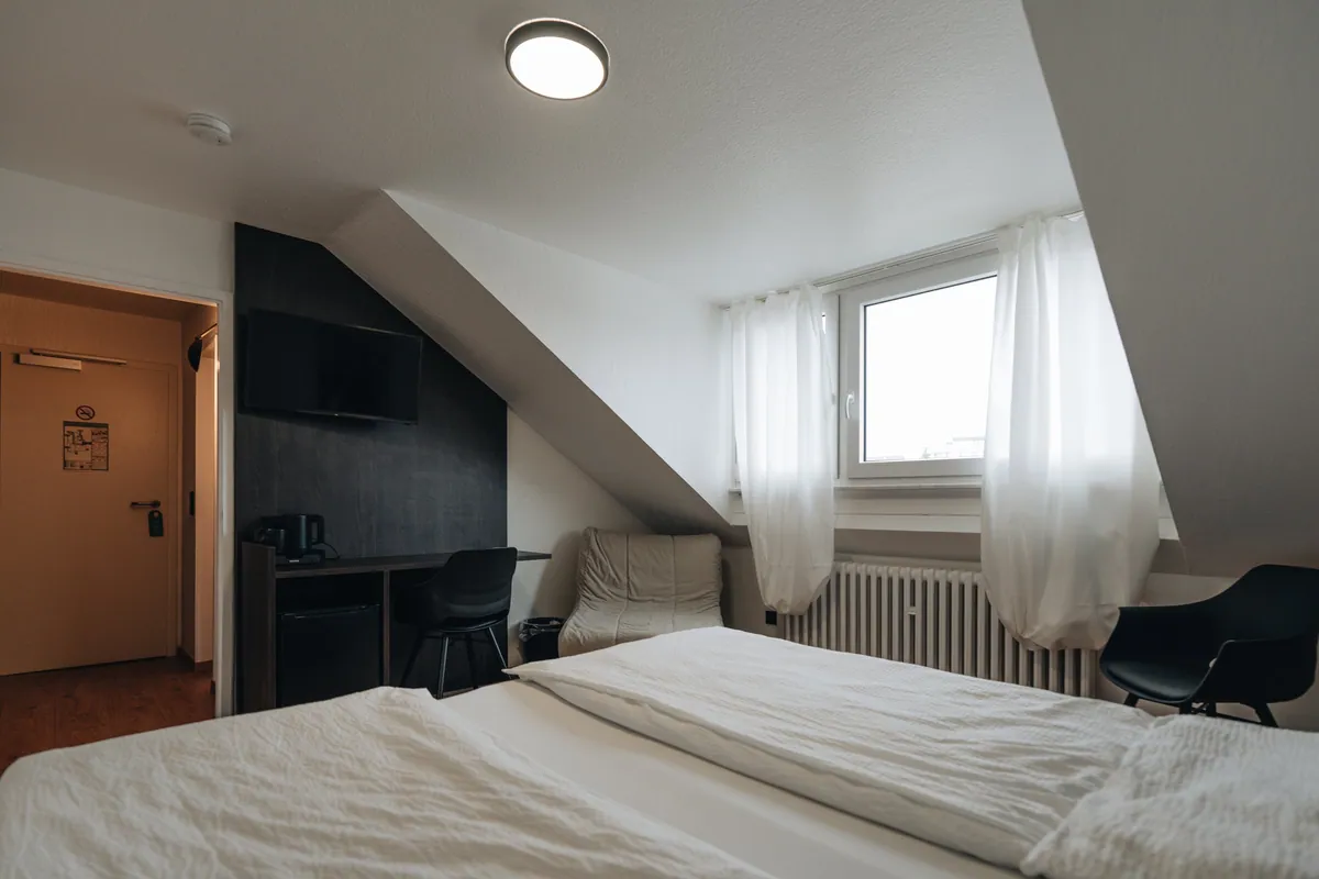 Dachzimmer mit Doppelbett und Sitzgelegenheit