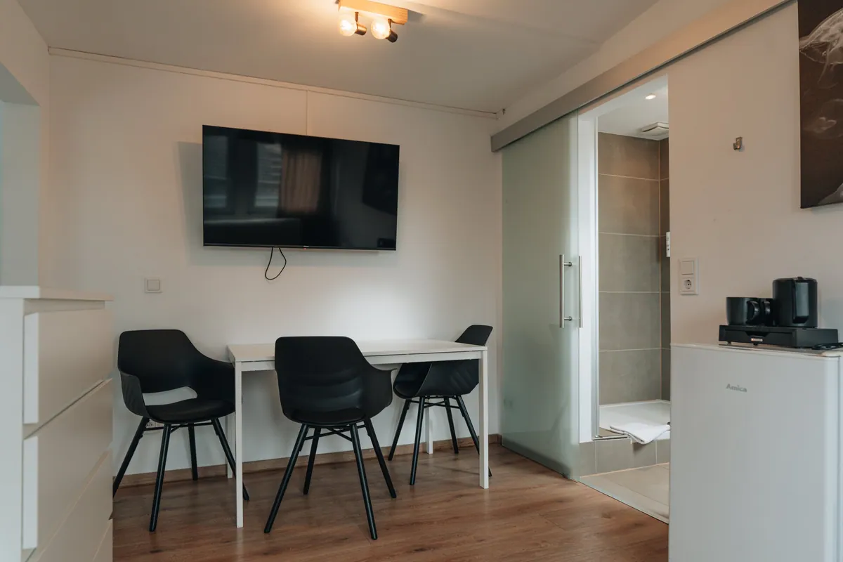 Zimmer mit Sitzecke, Fernseher und Schreibtisch