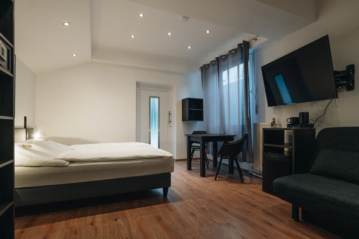 Hotelzimmer mit Doppelbett, Sofa und Fernseher